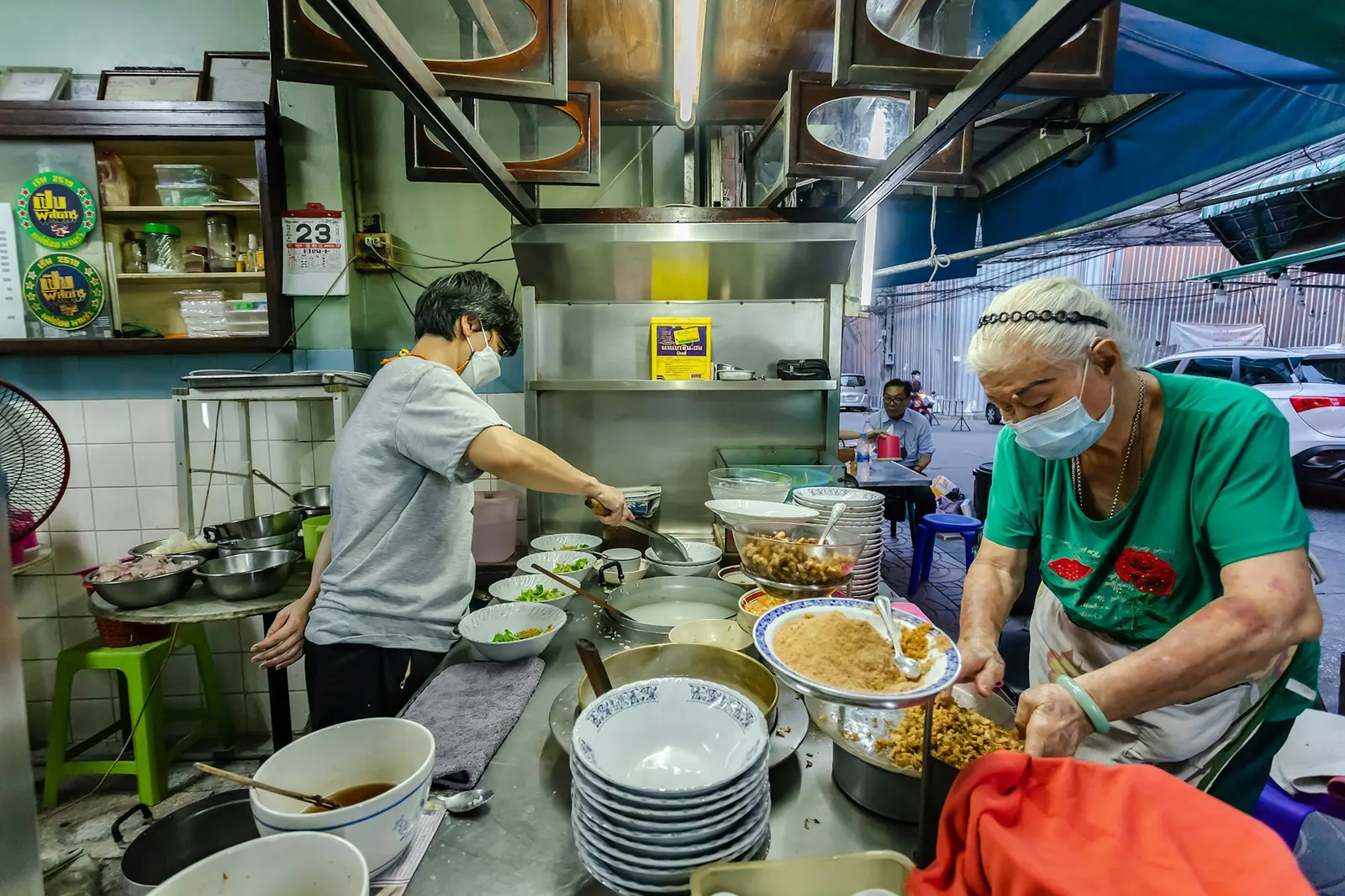 ร้านอาหารริมทางในไทย คนครัวกำลังเตรียมอาหารหลายถ้วยบนโต๊ะสแตนเลส